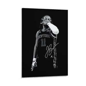 Puede incluir: Un retrato en blanco y negro de un jugador de baloncesto con una camiseta de New York con el número 11 y una manga blanca en el brazo. El jugador hace un gesto con la mano cerca de la cara. Una firma blanca es visible en la camiseta.