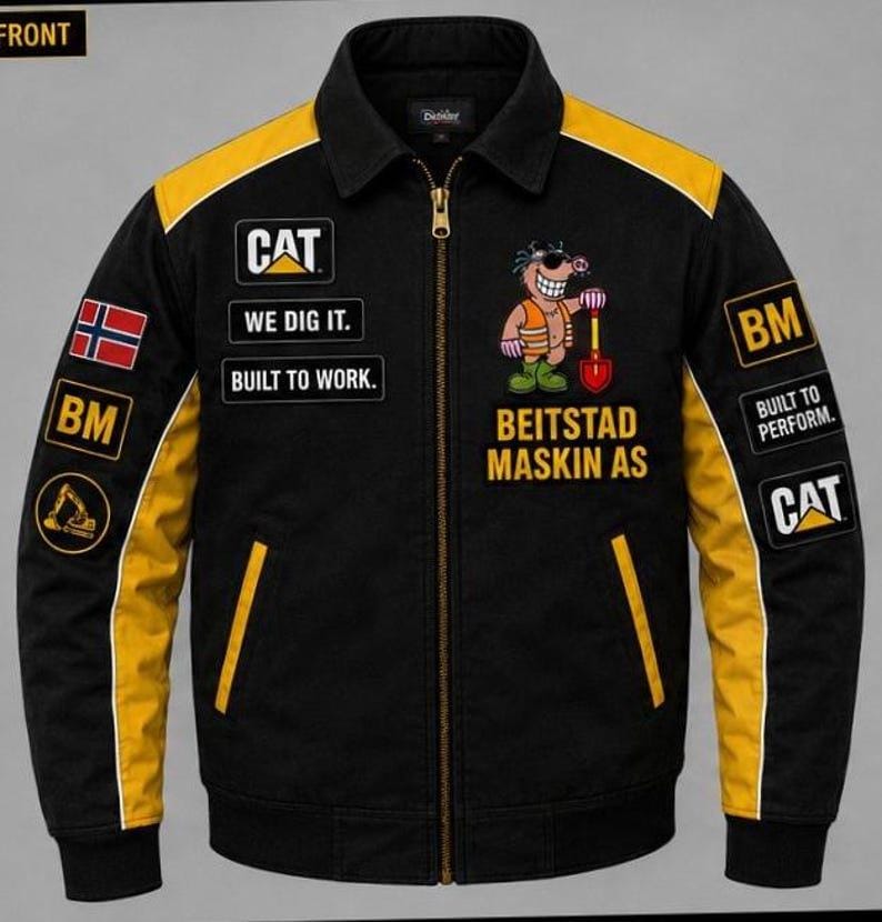 Puede incluir: Chaqueta de trabajo negra con detalles amarillos en los hombros y mangas. Cuenta con parches con el logo CAT, el texto "WE DIG IT" y "BUILT TO WORK". Tambi&eacute;n hay un personaje de dibujos animados con una pala, junto con el texto "BEITSTAD MASKIN AS."