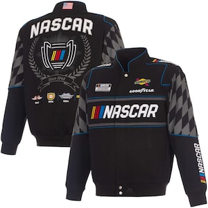Könnte beinhalten: Schwarze NASCAR-Jacke mit dem Wort "NASCAR" in Weiß auf der Vorder- und Rückseite. Auf der Rückseite befindet sich ein Logo mit Lorbeerkranz und dem Text "Since 1948". Grau-schwarzes Karomuster auf den Ärmeln.