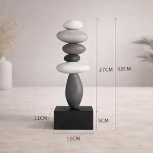 May include: A stacked stone sculpture with a black base, a dark gray elongated oval, and a series of gray and white oval stones. The sculpture is 12.6 inches tall and 4.3 inches wide. The base is 4.3 inches square and 2 inches tall.