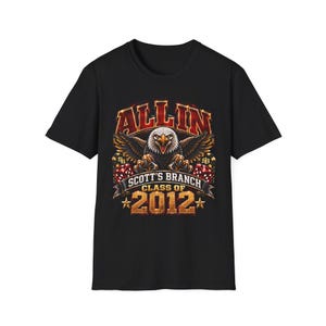 May include: A black short-sleeved t-shirt featuring a graphic print of a bald eagle with spread wings, red dice, and poker chips. The text reads ALL IN, SCOTT'S BRANCH, CLASS OF 2012, with gold stars on either side of the year in a bold font.