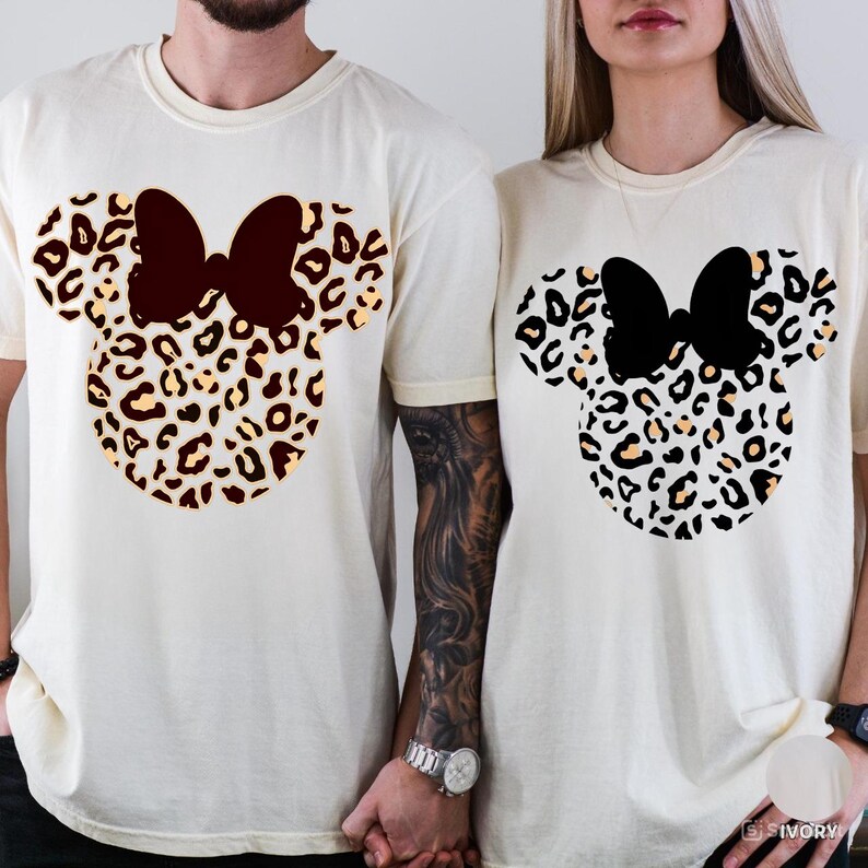 Puede incluir: Dos camisetas color crema con un dise&ntilde;o de Minnie Mouse. El dise&ntilde;o incluye una cabeza con estampado de leopardo y un lazo marr&oacute;n oscuro en una camiseta y un lazo negro en la otra. Las camisetas tienen mangas cortas y un corte holgado.