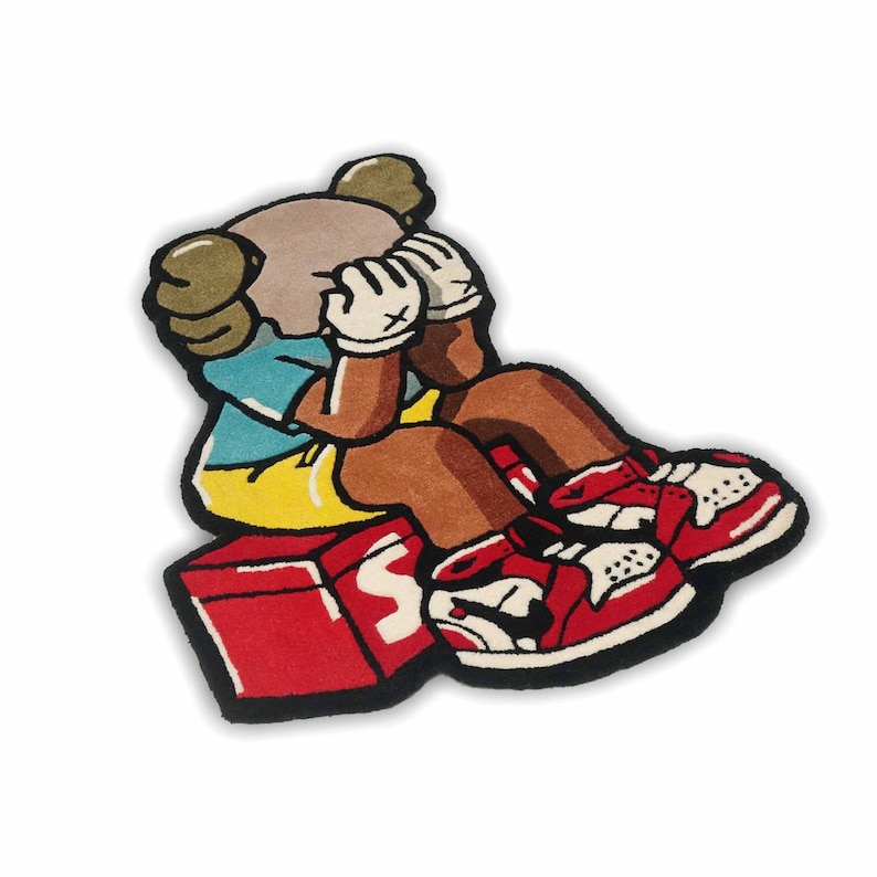 Puede incluir: Una alfombra de mechones con forma de personaje de dibujos animados con cabeza bronceada, camisa azul y pantalones cortos amarillos, sentada sobre una caja roja con una letra S blanca. El personaje lleva guantes blancos y zapatillas rojas y blancas.