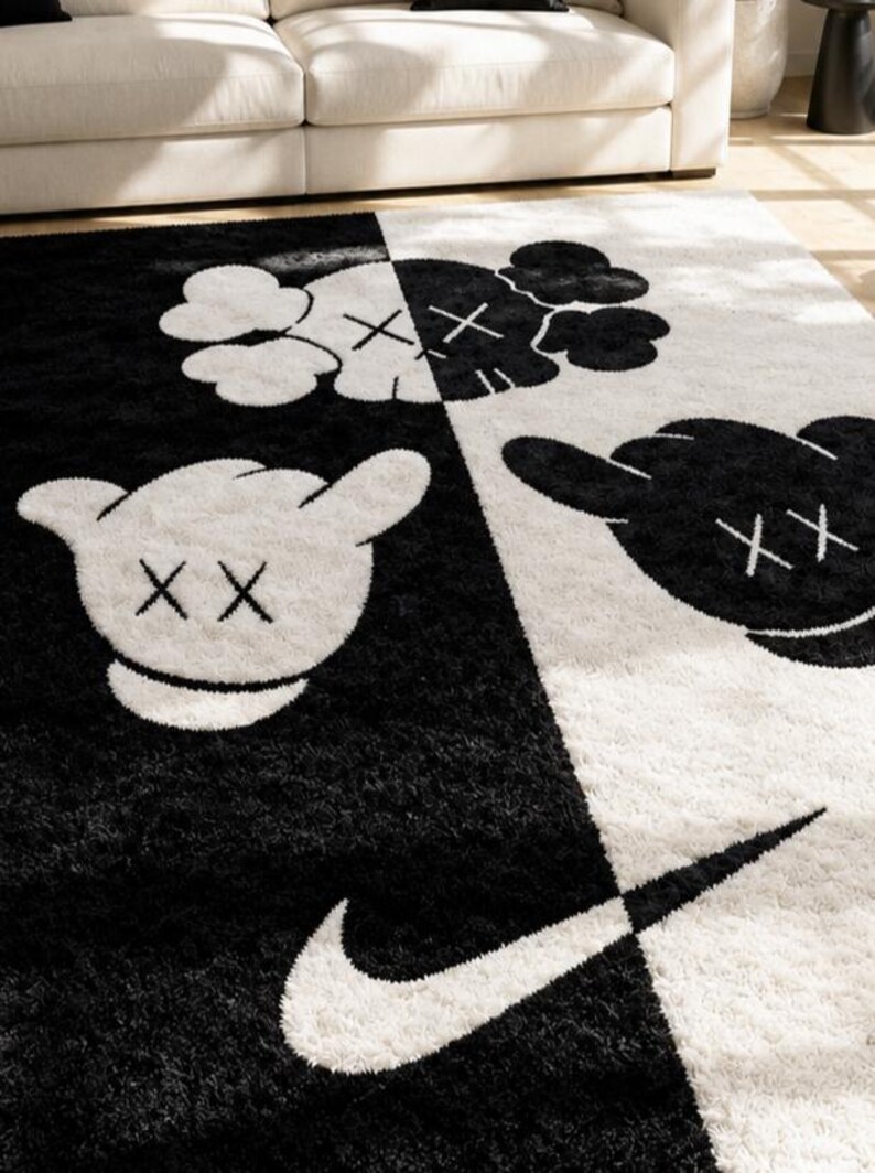 May include: A rectangular area rug featuring a split black and white design. The rug displays cartoon-style gloved hands with X-shaped eyes and a large swoosh logo. The surface has a thick, shaggy texture, contrasting the dark and light sections.