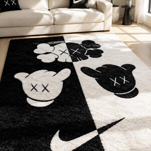 May include: A rectangular area rug featuring a split black and white design. The rug displays cartoon-style gloved hands with 'XX' eyes and a large Nike swoosh logo. The pattern is divided diagonally, with white graphics on the black side and black graphics on the white side, creating a high-contrast visual effect.