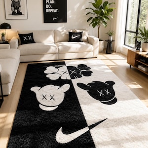 May include: A rectangular area rug featuring a split black and white design. The rug displays stylized cartoon character heads with X-shaped eyes and gloved hand motifs, along with a prominent white Nike swoosh logo positioned on the black section.