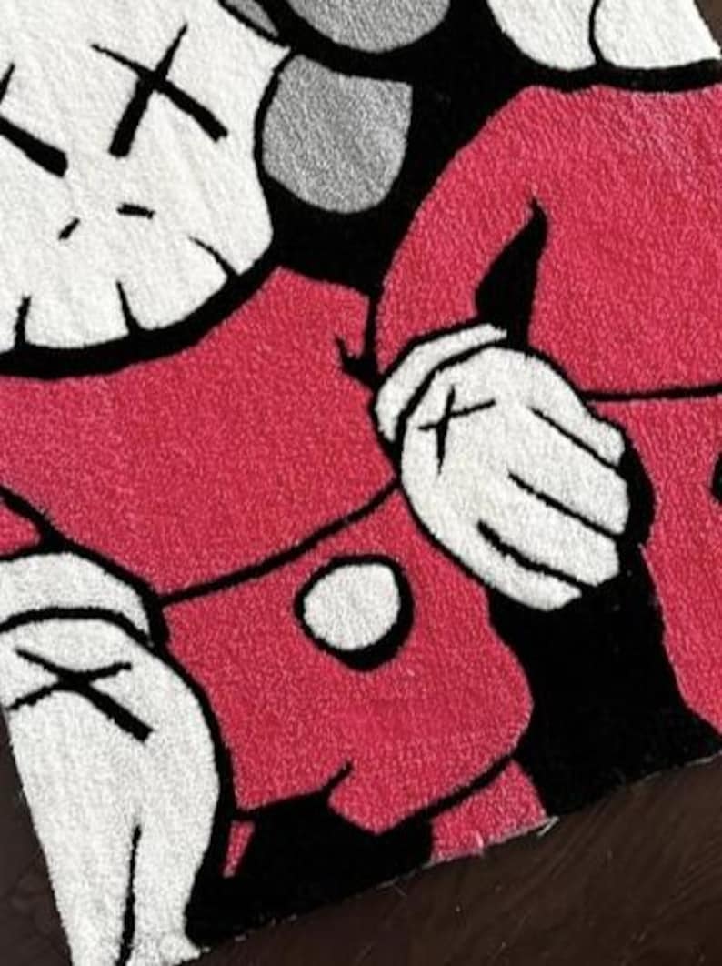 May include: A tufted rug featuring a graphic illustration of two cartoon-style figures with white heads, black X-shaped eyes, and white gloved hands. The figures are wearing red clothing with black accents, rendered in a textured, high-pile textile.