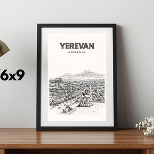 May include: Black framed print featuring a detailed black and white illustration of Yerevan, Armenia, with the city's name at the top. The print is displayed on a wooden surface, next to a gold desk lamp and a bouquet of flowers. The print size is 4x6 or 6x9 inches.