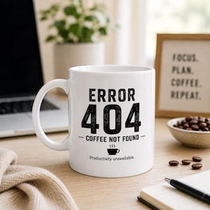 Puede incluir: Una taza de cerámica blanca con texto negro que dice ERROR 404 COFFEE NOT FOUND, un pequeño icono de una taza de café humeante y el texto Productivity unavailable. La taza tiene un asa curva y un acabado liso y brillante.