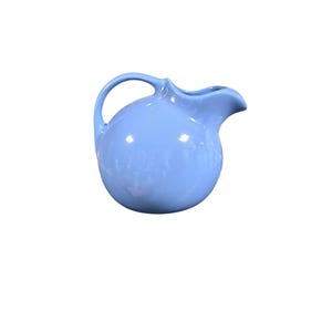 May include: A light blue ceramic pitcher with a rounded body, a curved handle, and a spout. The pitcher has a glossy finish and is designed for pouring liquids. This vintage-style pitcher is suitable for serving water or other beverages.
