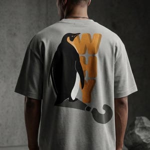 Puede incluir: Camiseta gris con un gráfico de pingüino y la palabra "WHY" en naranja. El pingüino es blanco y negro, y la camiseta tiene un corte holgado. La camiseta está hecha de un material suave.
