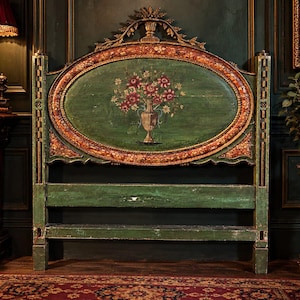 Puede incluir: Un cabecero de madera verde con un panel central ovalado que presenta un arreglo floral pintado a mano en un jarrón. El marco está decorado con detalles en tono dorado y una cresta tallada en la parte superior, sostenido por dos postes verticales.