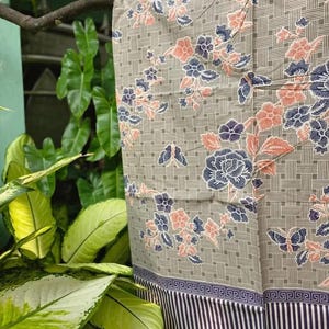 Peut inclure: Un tissu présentant un fond brun clair avec un motif de grille tissée, orné de motifs floraux et de papillons dans des tons bleu foncé et pêche. Le bord inférieur présente une bordure à rayures verticales bleu foncé et blanches.