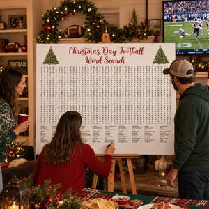 Op de afbeelding: Een grote witte poster op een houten ezel met een kerst-voetbal-woordzoekspel, rode tekst, groene boomafbeeldingen en een raster van letters. De lijst met woorden die gezocht moeten worden staat onderaan het spelbord afgedrukt.