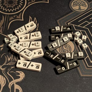 Puede incluir: Un conjunto de piezas de juego blancas y negras, que incluyen dados y bandejas con marcas numéricas y símbolos matemáticos. Los dados muestran números del 1 al 6. Las bandejas tienen símbolos de suma, resta y división.