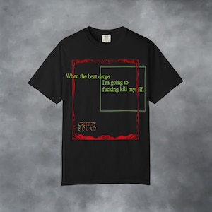 Puede incluir: Una camiseta negra de manga corta con un marco rectangular rojo ornamentado y un fino contorno cuadrado verde. El texto dice: When the beat drops I'm going to fucking kill myself. Las palabras Cruelty Squad aparecen en dorado abajo a la izquierda.
