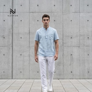 May include: A light blue short-sleeve shirt with a mandarin collar and a chest pocket, paired with white pants and white sneakers. The shirt has a button-up placket. The brand name "NAYFOR" is visible in the upper left corner.