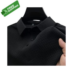 Pode incluir: Camisa preta com gola e padr&atilde;o de tecido texturizado. A camisa tem uma frente abotoada e uma gola cl&aacute;ssica. O tecido parece ser um material de peso m&eacute;dio.