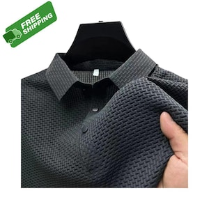 Pode incluir: Camisa cinza escuro com gola e um padr&atilde;o tecido texturizado. A camisa tem uma frente abotoada e &eacute; exibida em um cabide preto. A imagem inclui uma faixa verde com as palavras "FREE SHIPPING".