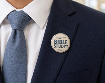 May include: A circular pinback button featuring a cream-colored background with dark blue text that reads WOULD YOU LIKE A FREE BIBLE STUDY? and a small icon of an open book, pinned to the lapel of a dark navy blue suit jacket with a white shirt.