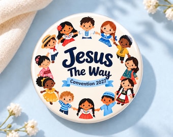 May include: A round button featuring a cream-colored background with a central illustration of diverse children holding hands in a circle. The text reads "Jesus The Way" above a blue banner with the text "Convention 2027" in dark blue.