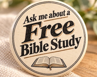 May include: A round pinback button with a cream-colored background and black text that reads Ask me about a Free Bible Study. The design includes a black line illustration of an open book at the bottom and a double-line circular border.