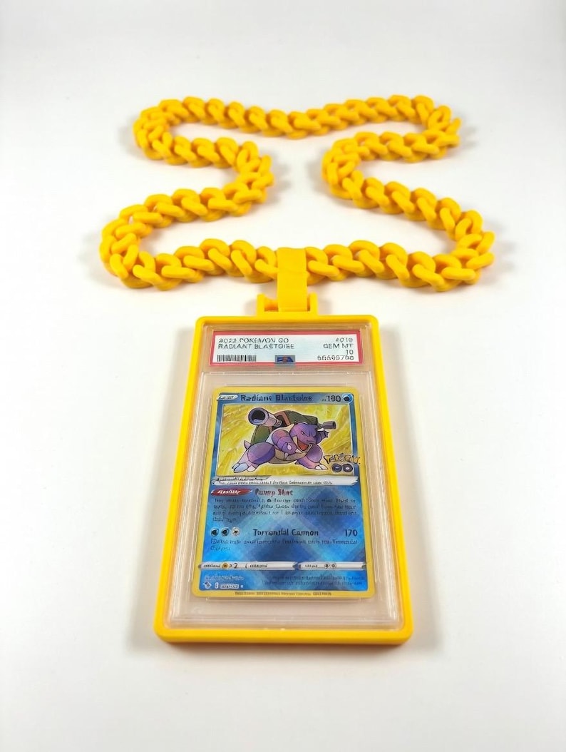 Może przedstawiać: Jasnoż&oacute;łty naszyjnik z wisiorkiem z kartą Pok&eacute;mon. Karta przedstawia niebiesko-fioletową ilustrację Blastoise z napisem "Radiant Blastoise". Wisiorek i naszyjnik wykonane są z ż&oacute;łtego materiału.