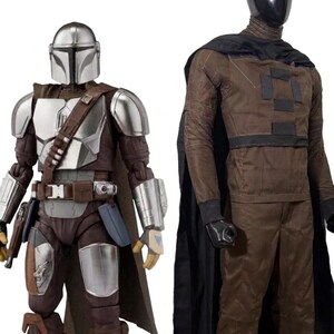 May include: A Mandalorian action figure with a silver helmet and armor plates over a brown suit, standing next to a mannequin wearing a brown long-sleeved shirt, brown trousers, and a black cape, both displayed against a plain white background.