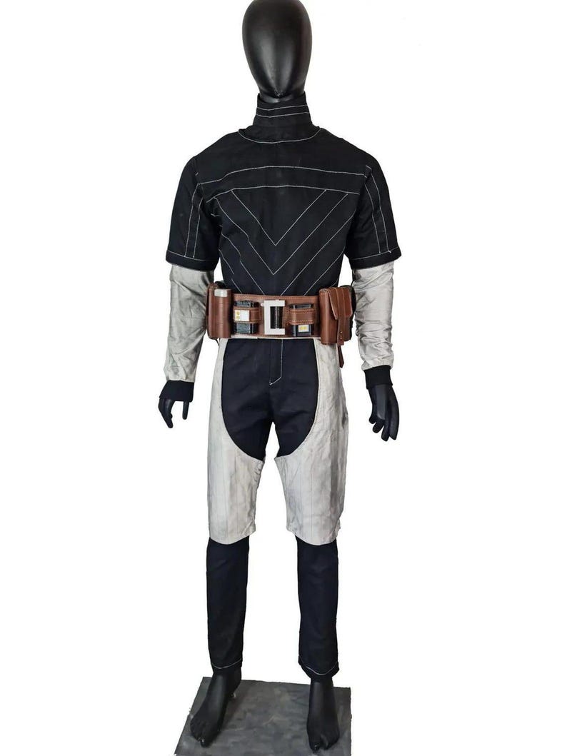 May include: A black and light gray jumpsuit featuring a high collar, short sleeves, and a fitted silhouette. The garment includes a brown utility belt with multiple pouches and a central metallic buckle, worn over the waist of the jumpsuit.