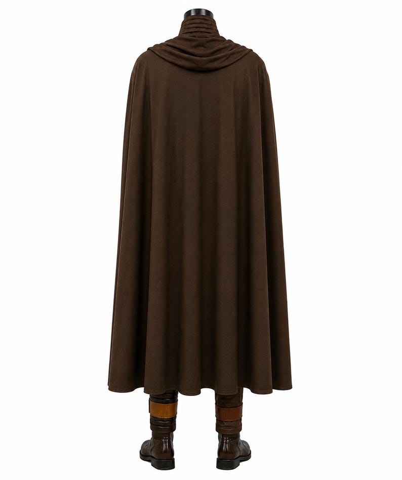 May include: A floor-length brown cloak featuring a hood with a gathered neckline and a smooth, solid-colored fabric. The garment hangs straight down, partially obscuring a pair of dark brown boots with tan straps visible at the bottom hem.
