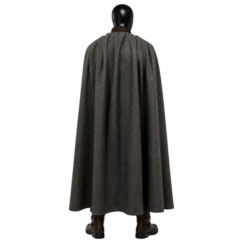 May include: A floor-length charcoal gray wool cape featuring a dark brown leather collar. The cape is draped over a black mannequin head and shoulders, paired with dark brown leather boots that have side buckle closures and a low heel.