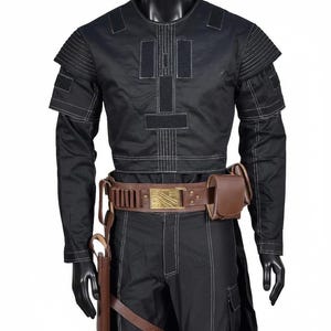 May include: A black long-sleeved shirt with white contrast stitching, shoulder padding, and rectangular hook-and-loop patches. A brown leather utility belt with a metallic buckle, ammunition loops, a side pouch, and a holster is worn at the waist.