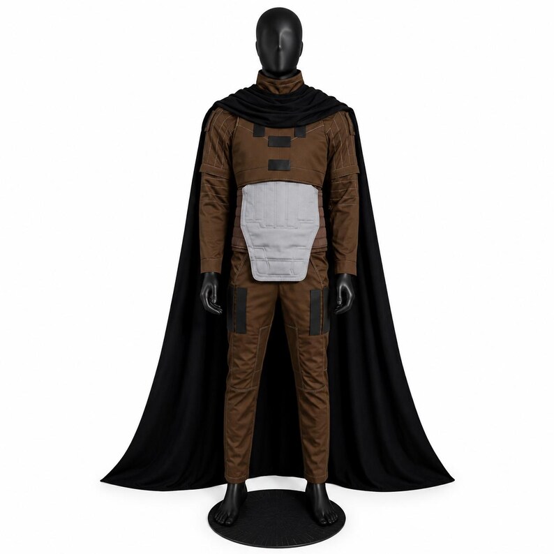 May include: A brown long-sleeved jumpsuit with a high collar, featuring a light gray abdominal armor plate and black rectangular accents on the chest and thighs. A long black cape drapes from the shoulders over the brown jumpsuit ensemble.