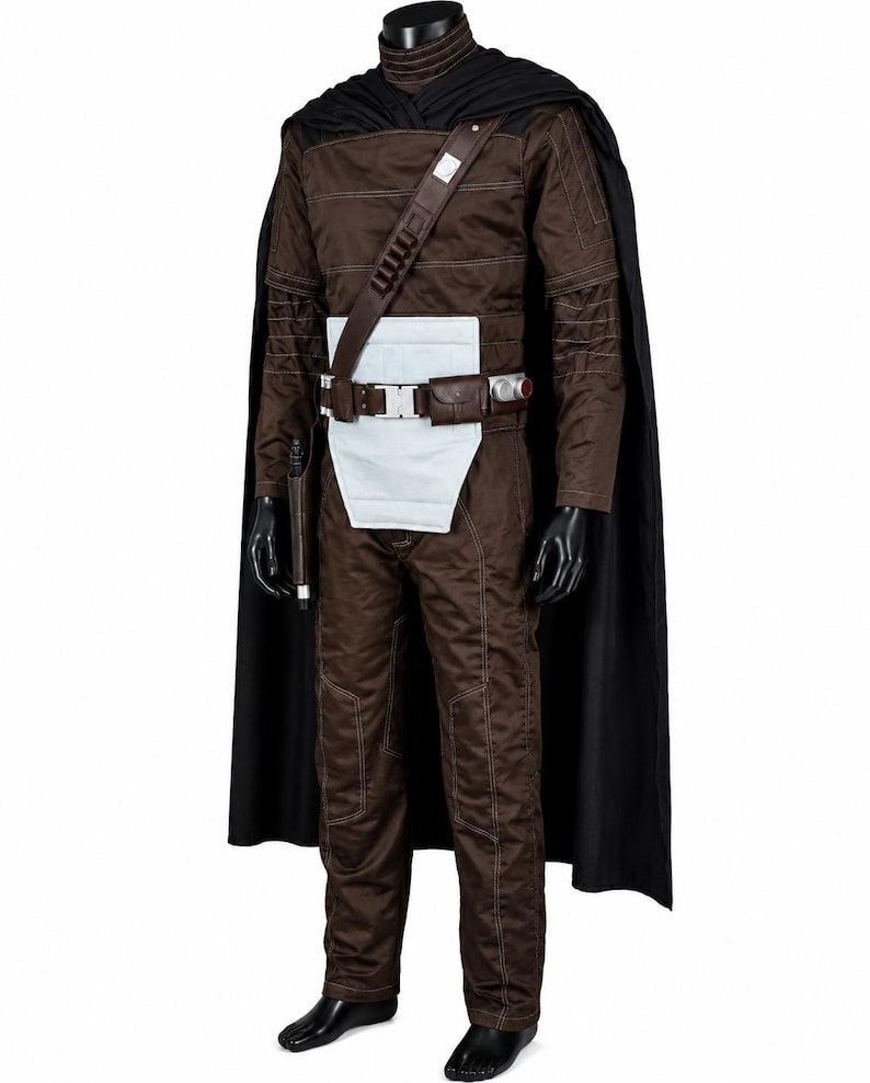 Puede incluir: Un mono marr&oacute;n de manga larga con detalles de costuras blancas, combinado con una capa negra, un panel de cintura rectangular blanco y un cintur&oacute;n utilitario marr&oacute;n con hebilla plateada, una peque&ntilde;a bolsa y una funda para un accesorio.