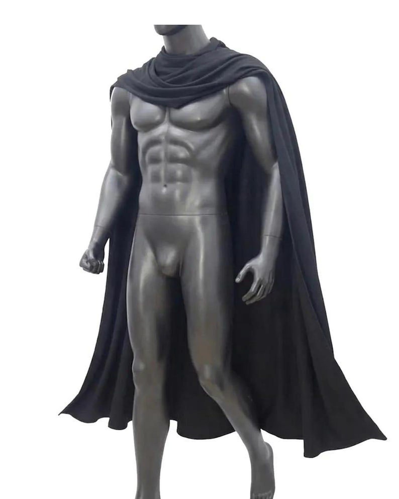 May include: A solid black cape featuring a draped neckline that secures around the shoulders and extends down the back. The fabric is opaque and hangs in soft, vertical folds, covering the shoulders and upper back while flowing freely downward.