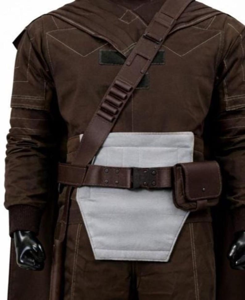 May include: A dark brown long-sleeved jacket with a light gray rectangular abdominal panel, a dark brown utility belt with a side pouch, and a matching brown shoulder strap featuring five small cylindrical loops across the chest area.