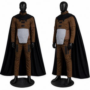 May include: A brown long-sleeved shirt and matching pants costume set featuring a black cape, a light gray abdominal armor piece, and black rectangular accents on the chest and legs, displayed on a black mannequin in front and side views.