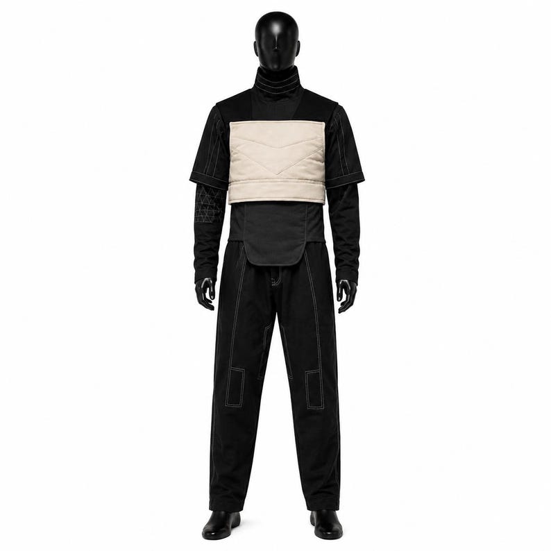 May include: A black high-neck short-sleeve shirt with white contrast stitching, featuring a beige quilted chest panel. The outfit includes matching black trousers with white contrast stitching and rectangular knee detailing, displayed on a mannequin.