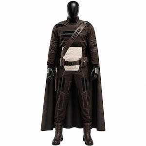 May include: A dark brown costume set on a mannequin, featuring a long cape, a long-sleeved top with geometric sleeve patterns, a cream-colored quilted midsection, a utility belt with pouches, dark trousers, and brown boots with buckle straps.