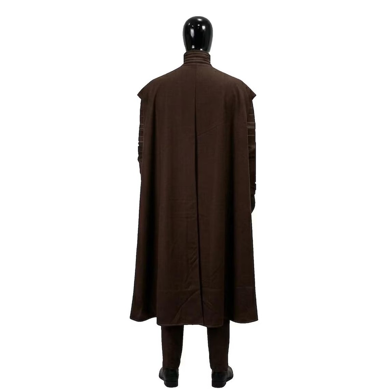 May include: A dark brown floor-length cape with a high collar worn over a matching long-sleeved garment and trousers. The cape features a vertical center seam and structured shoulders, displayed on a black mannequin against a white background.