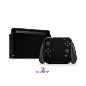 Może przedstawiać: Czarny zestaw konsoli do gier i kontrolera. Konsola jest prostokątna z ekranem i podstawką. Kontroler jest czarny z przyciskami i joystickami. Logo Skinify znajduje się na dole.