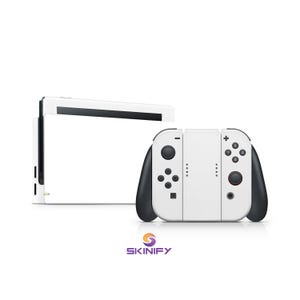 May include: White and black Nintendo Switch console with attached Joy-Con controllers. The controllers have black grips and buttons. The console is white with black accents. The Skinify logo is at the bottom.