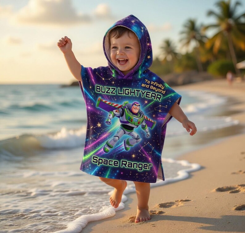 May include: A child's hooded poncho featuring Buzz Lightyear, in purple, blue, and green. The poncho has the words "Buzz Lightyear" and "Space Ranger". The background design is a starry night sky. The child is on a beach.