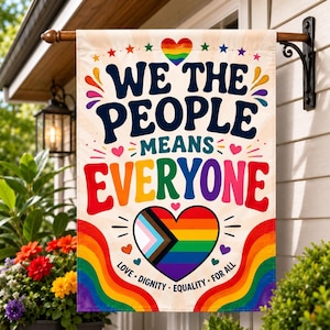 May include: A rectangular garden flag featuring the text WE THE PEOPLE MEANS EVERYONE in dark blue and multicoloured lettering. A central heart displays the Progress Pride flag colours. The bottom includes the words LOVE DIGNITY EQUALITY FOR ALL.