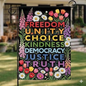 May include: A black garden flag featuring the words "FREEDOM, UNITY, CHOICE, KINDNESS, DEMOCRACY, JUSTICE, TRUTH" in rainbow colours. The flag is decorated with daisies, tulips, and other flowers. The flag is designed for outdoor use.