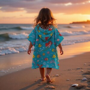 May include: A turquoise hooded beach towel featuring a mermaid and other sea creatures. The towel is worn by a child walking on a sandy beach at sunset. The towel's design includes fish, starfish, and seashells.