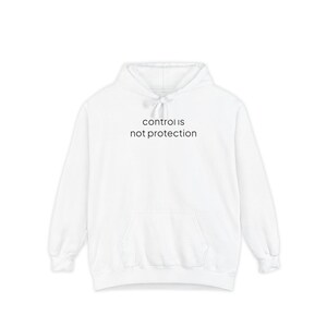 May include: A white long-sleeve hooded sweatshirt featuring a front kangaroo pocket and a drawstring hood. The text "control is not protection" is printed in black, sans-serif lowercase letters across the centre of the chest area.