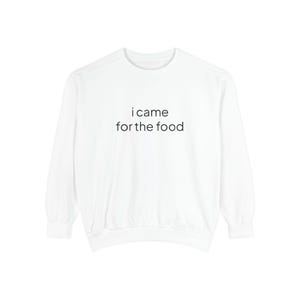 May include: A white long-sleeve crewneck sweatshirt featuring the black text i came for the food printed in the center of the chest. The garment has a ribbed neckline, cuffs, and hem, with a simple, clean design and a standard pullover fit.