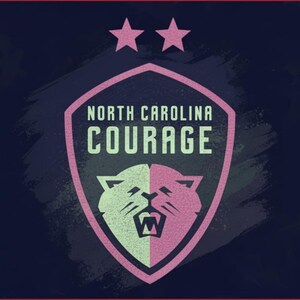 May include: A shield-shaped logo for the North Carolina Courage soccer team. The logo features a pink and white cougar head, the team name, and two pink stars on a navy blue background. The design has a distressed, textured look.