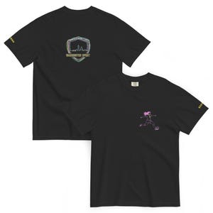 May include: Black t-shirts with soccer designs. One shirt displays a neon outline of a soccer player kicking a ball. The other has a neon outline of a shield with the words "Washington Spirit" and a skyline.